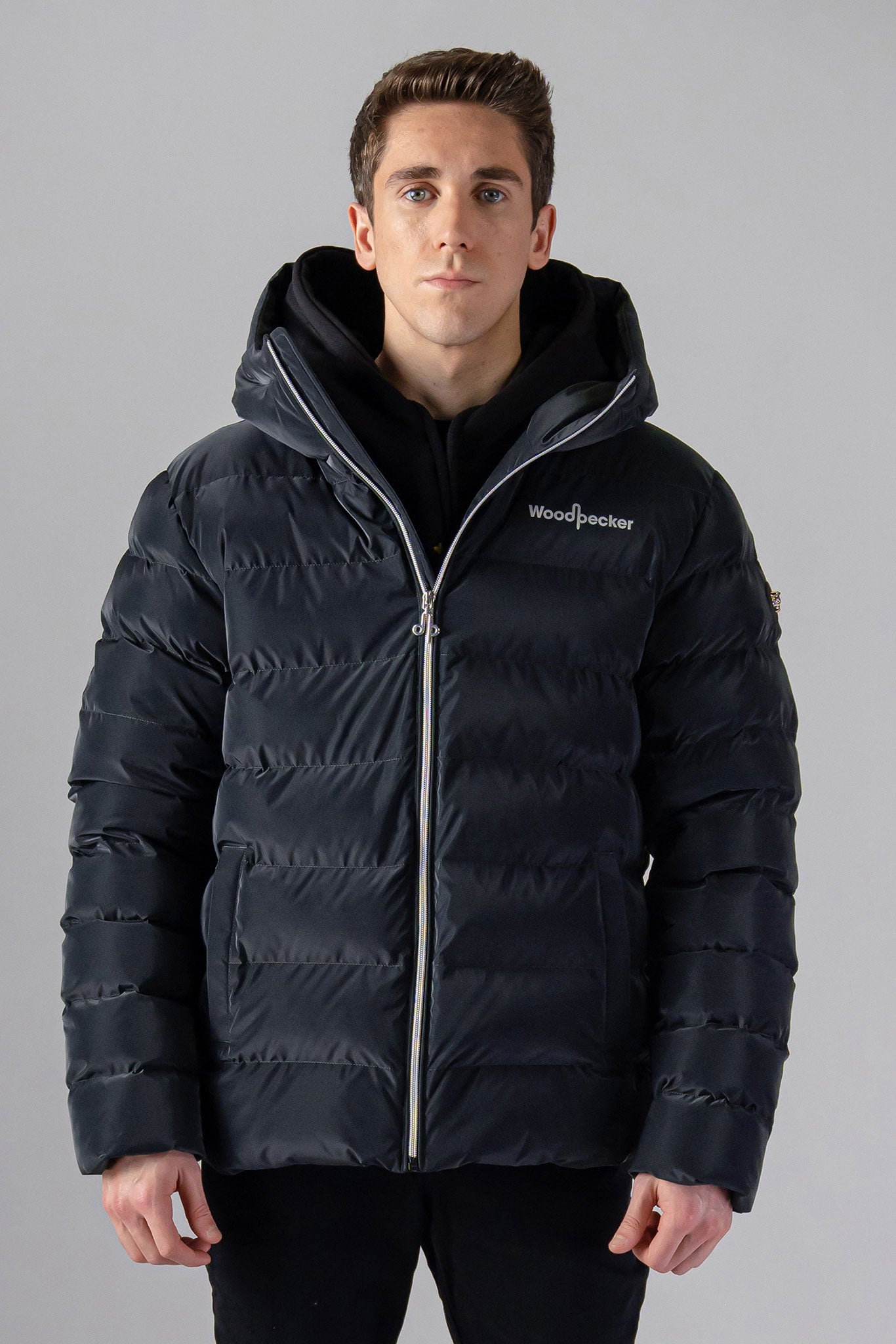 Woodpecker Men's Sparrow Winter coat. High-end Canadian designer winter coat for men in "Black Diamond" colour. Woodpecker cruelty-free winter coat designed in Canada. Men's medium weight medium length premium designer jacket for winter. Superior quality warm winter coat for men. Moose Knuckles, Canada Goose, Mackage, Montcler, Will Poho, Willbird, Nic Bayley. Shiny parka. Stylish winter jacket. Designer winter coat.