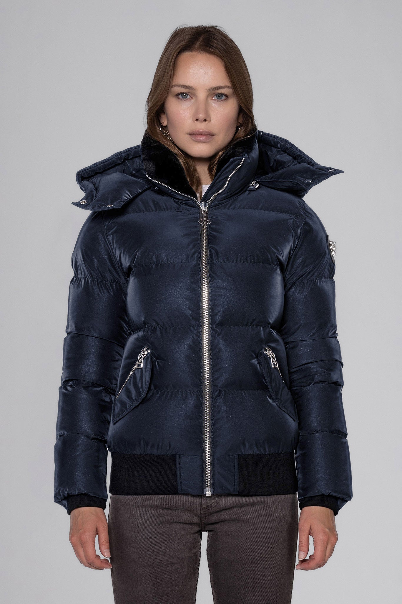 Woodpecker Women's Woody Bomber Winter coat. High-end Canadian designer winter coat for women in "Blue Diamond" colour. Woodpecker cruelty-free winter coat designed in Canada. Women's heavy weight short length premium designer jacket for winter. Superior quality warm winter coat for women. Moose Knuckles, Canada Goose, Mackage, Montcler, Will Poho, Willbird, Nic Bayley. Shiny parka. Stylish winter jacket. Designer winter coat.